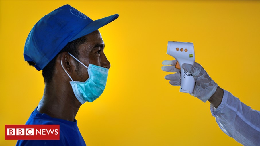 Man has his temperature taken by an Indonesian health officer