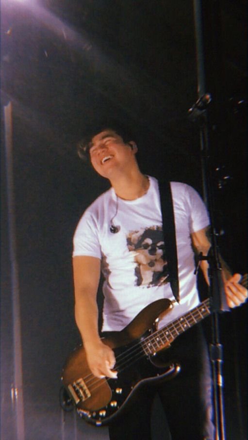 calum smiling while playing his bass :)