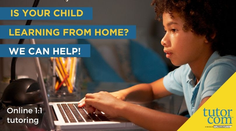 a child sitting down at a desk looking at a laptop. young elementary school age boy
