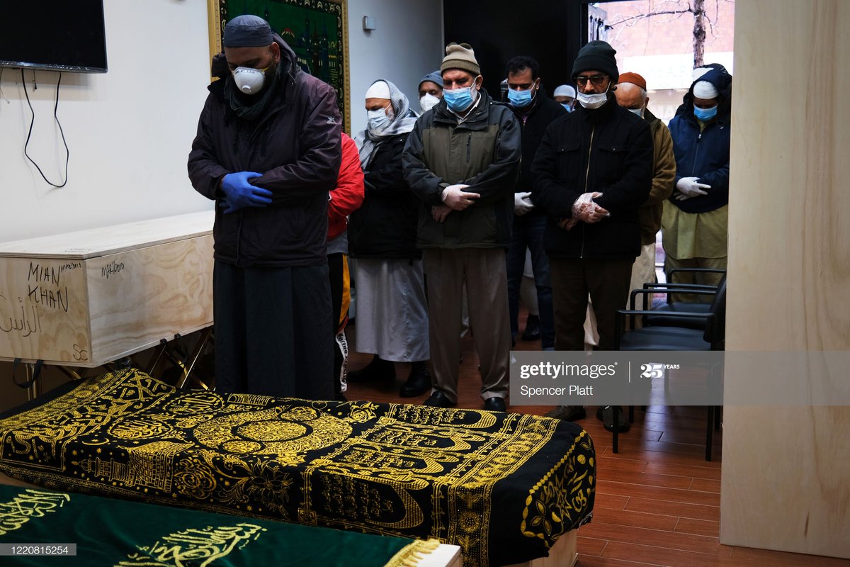 Muslim men participate in a brief funeral prayer service at a busy