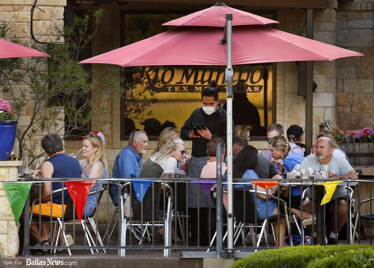 On the first day of restaurants outdoor patios being reopened in Colleyville, Texas "so long as physical distancing is maintained between tables," a waiter wearing a face mask takes orders from diners eating on the outdoor patio at Rio Mambo Tex Mex.