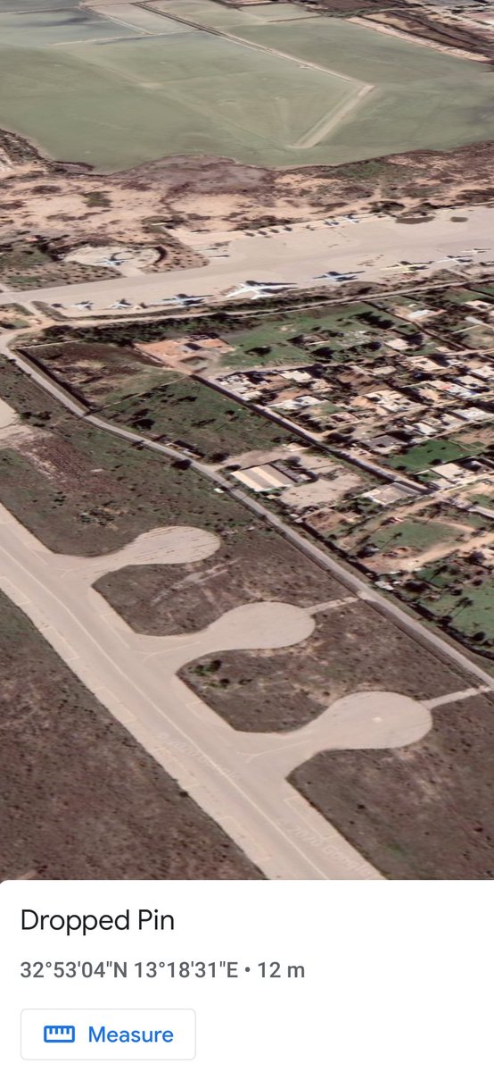 Using the pin as the focal point, I tried to determine what was smoking so badly. The direction of view has 3 apron circles and a tarmac beyond. Many of these aircraft on the tarmac are derelict. There are also residential areas in between.