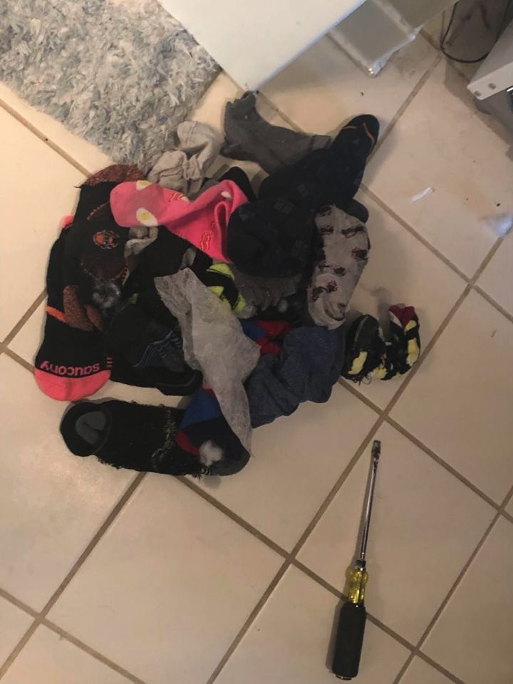 He keeps reaching until finally he pulls out this gigantic pile. This, right here, is what broke our washer: About a year's worth of missing socks. (6/?)