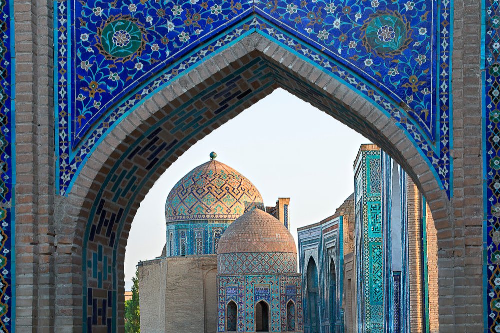 View over the mausoleums and domes of the historical cemetery of Shahi Zinda (Persian "The Living King") through an arched gate, Samarkand.
