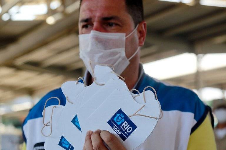 oatila's tweet photo. Prefeitura do Rio distribuindo esse tipo de máscara de papelão? Nem a pessoa distribuindo acredita nisso. Parece culto à carga. E pra quem não conhece culto à carga, segue um pequeno fio. 
 https://t.co/dF70JyZ6JC https://t.co/qRwS0NeF9Q