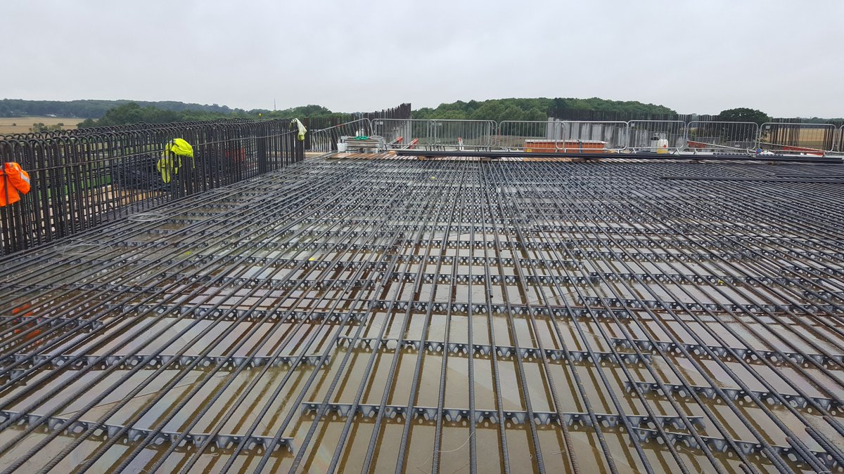 Rebar fixing for the deck bottom mat in August 2017; here the bottom layer of rebar has been fixed, on the left the sides are installed - the slab was between 1.2-1.5m thick! Plastic grey strips are spacers to keep the rebar off the wood & ensure good embedment into concrete 21/