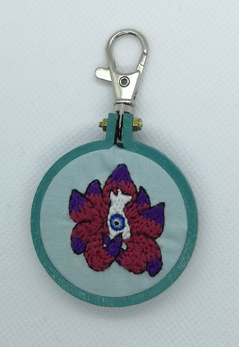 A 5cm custom keychain, a nine tailed fox with an evil eye within it, mounted into a hand painted hoop