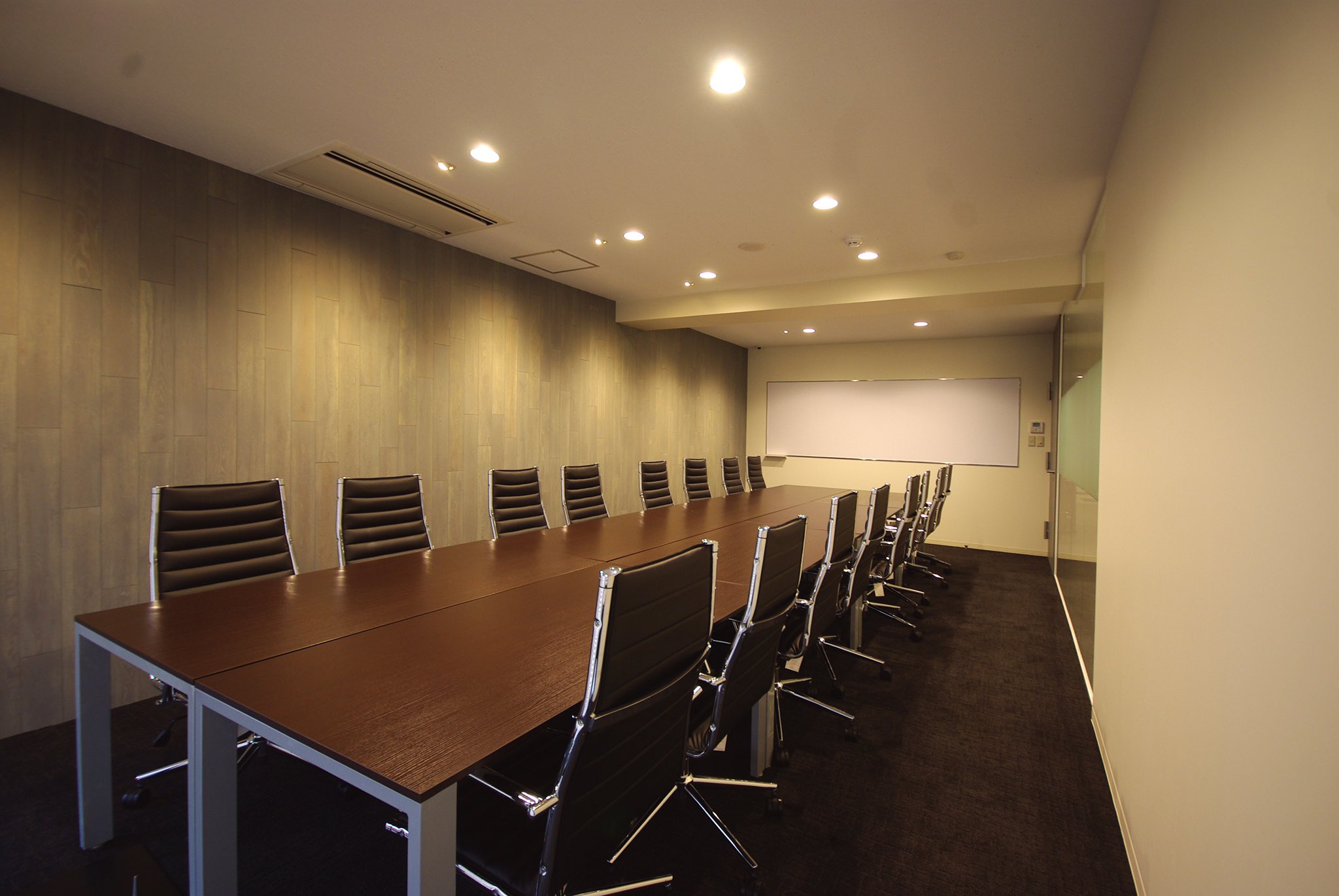 株式会社フレームス フレームス デザイン事例 こちらは16人で会議ができる大きめのミーティングルーム 統一感を出すため 壁の羽目板はエントランス正面と同じものを使いました 色味がアッシュグレーなので オレンジ味の強い木材よりもシャープな