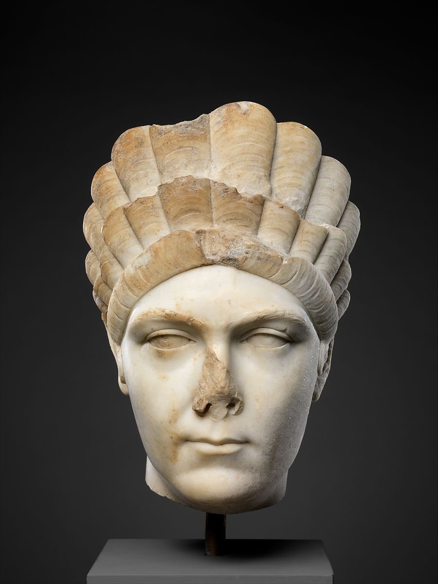 ‪Front view of Roman marble portrait of Marciana, sister of Trajan ~ c. 130–138 CE‬. The skin and eyes are smoothly polished, while the hairstyle (or front-piece at least!) extends high above the forehead.