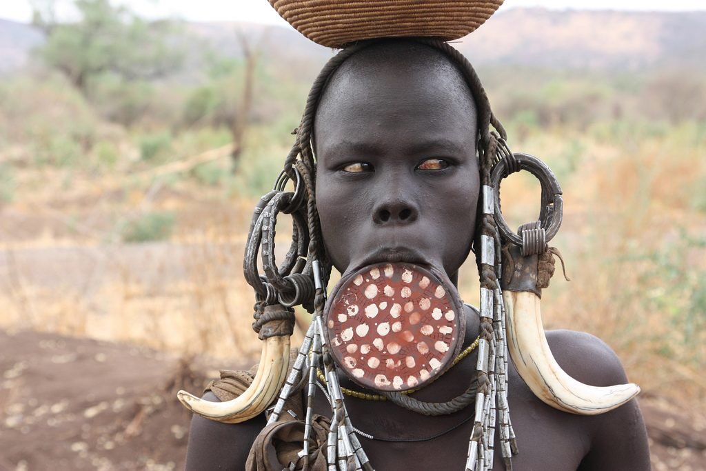 6. A Wakandan elder in the throne room wears a lip plate which draws inspiration from the Mursi culture in Ethiopia - also seen among Chai and Tirma. Seen as a source of pride and also identity. Typically worn by women, but worn by a man in the film.Film  Original 
