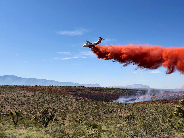 Airtanker dropping red fire retardant along the hot fire flank.