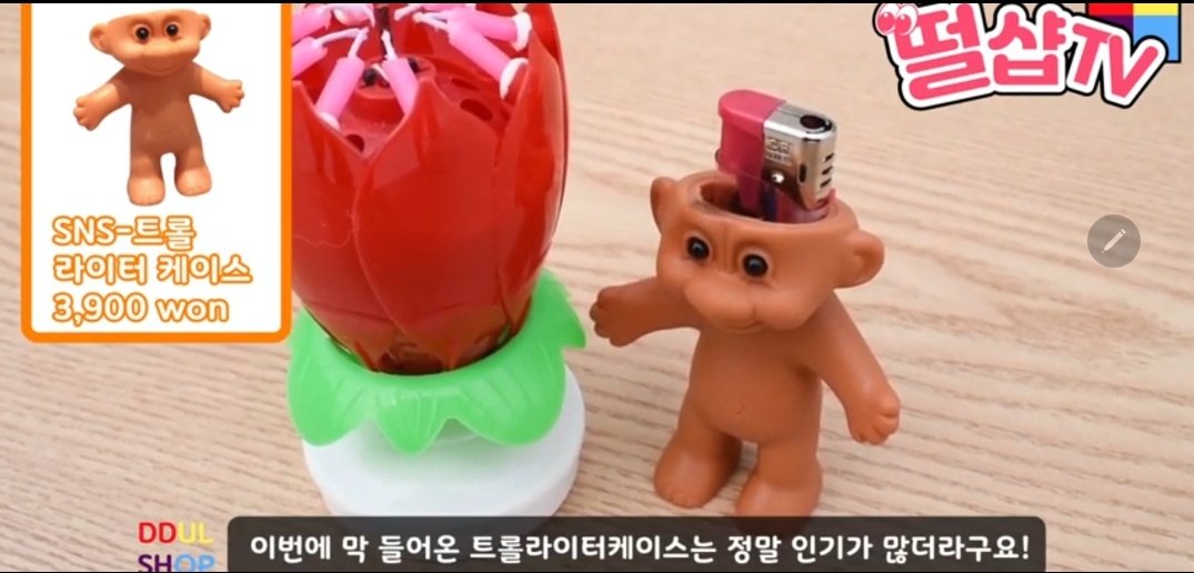 J.k didn't bought that troll lighter case that was most probably bought by her in Korea.That troll is being sold in online shops like ebay.They sell this in Korea too and seems pretty famous there.She was in a commercial area in Busan where she probably bought it.
