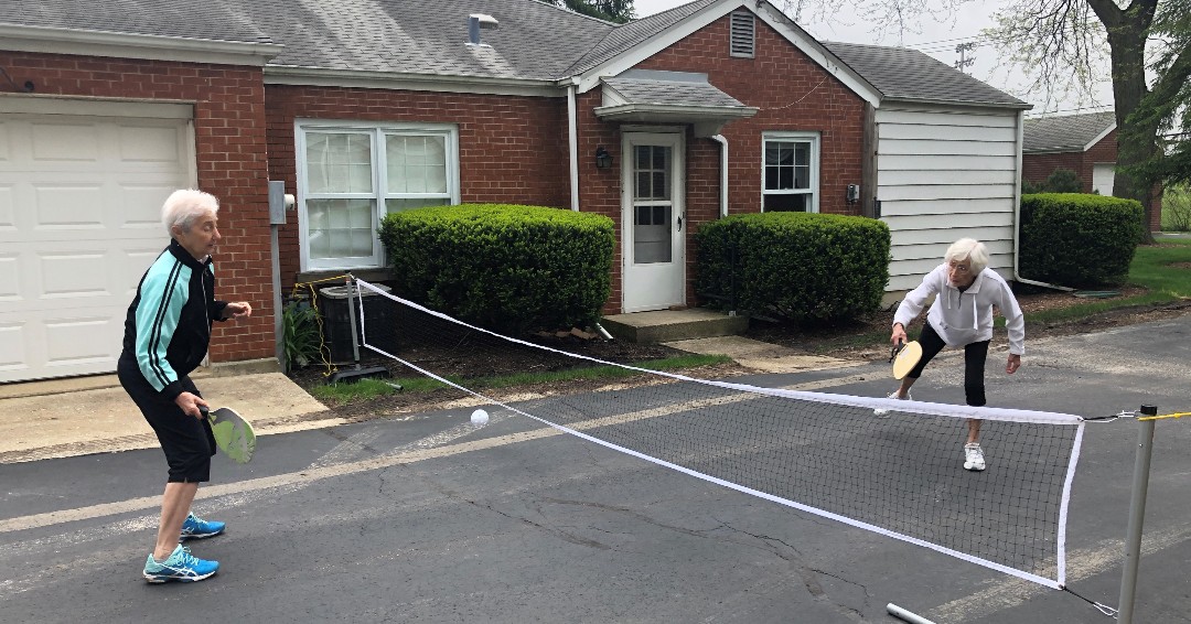 PlymouthPlace's tweet photo. What do you get when you mix tennis, badminton and ping-pong - besides a good workout? PICKLEBALL! A couple of our residents enjoyed a friendly game of pickleball...look at the form on that serve! 🥒🏓 #Ace https://t.co/IqdVFTw4Rq