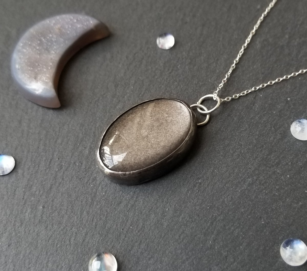 BLaceJewelry's tweet photo. The Cosmos Pendant, a shimmery vortex of grey obsidian! 💫
The way this stone reacts to light is truly amazing! The backside of the pendant features a cut-out image of a galactic swirl. 
https://t.co/PPDwIk6gv9

#galaxy #Space #jewelry #Pendant #tuesdayvibes #artist #stars https://t.co/QygdtjLxUl