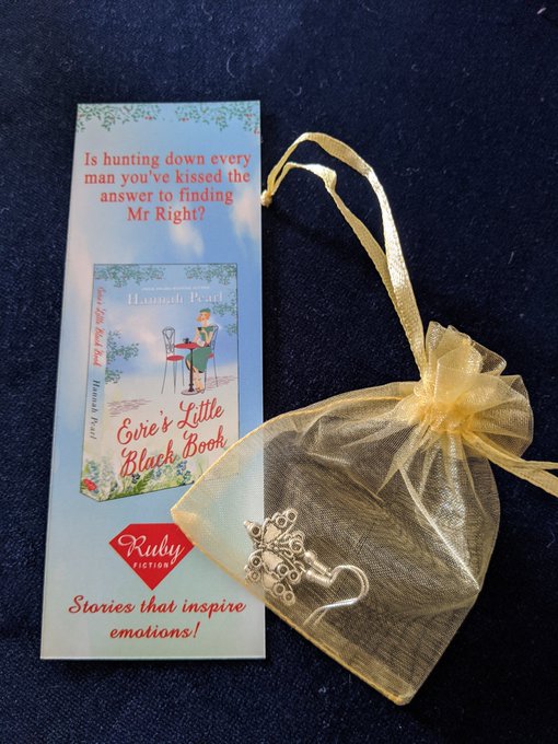 Picture of a book mark for Evies Little black book and a pair of silver coloured earrings in an organza bag