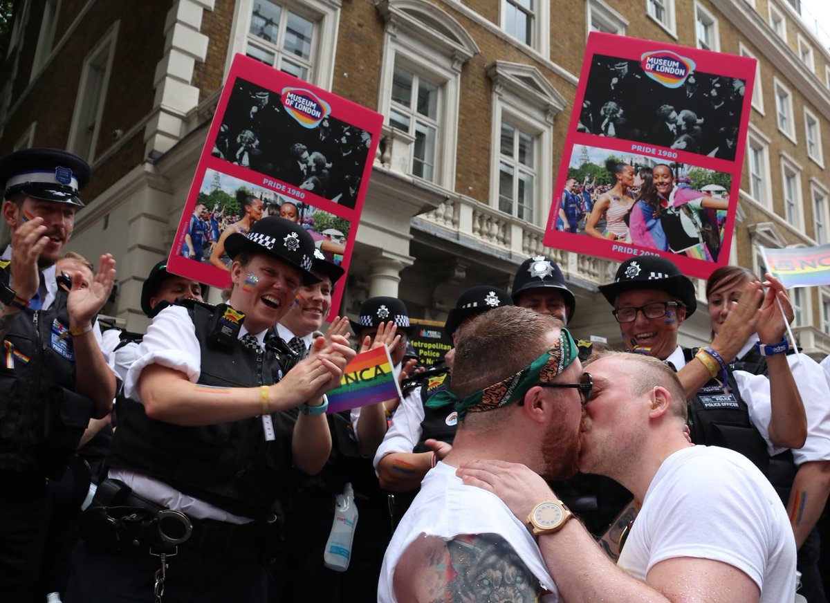 QueerBritain's tweet photo. Here’s the pic I snapped @PrideInLondon that recreated the photo of an early Pride on the @MuseumOfLondon placards, with a twist.
For @MuseumPrideLdn our co-chair Rob @BritishLibrary and his partner recreated the moment with the police applauding #QBLockdownHunt #DanVo https://t.co/s9n6KPburX
