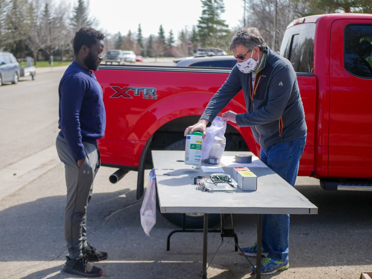 UofRegina's tweet photo. This morning, #UofRegina Lab Instructor Dave Duguid - complete with bagpipes - went all out to ensure #Engineering students, including Abraham Mugerwa, stopped by to pick up kits that will allow them to do their Electronic Systems Engineering labs while safely at home. https://t.co/U7HImB10dg