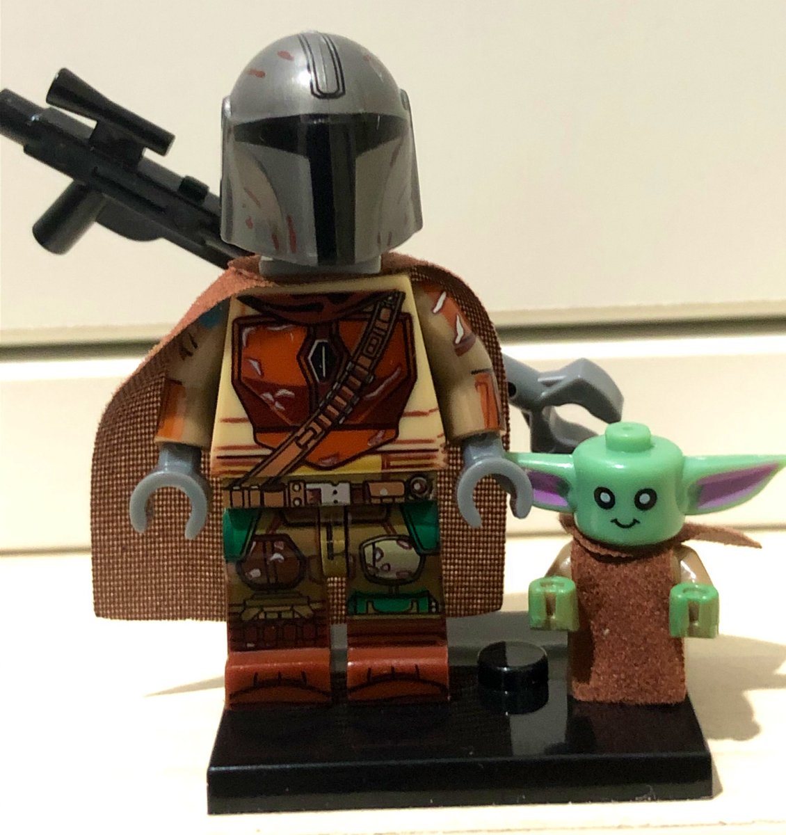 OneDollarLego's tweet photo. You might have guessed what it is. It’s The #Mandalorian from the MW brand. In his beat up armour of course.

And what’s #Mando without #BabyYoda!

Fits into his hand. The body is based on #Lego’s baby body. Head is custom. 3 cloth capes: 1 for Mando and 2 for Baby.

#LegoWill https://t.co/epBWNDUicP