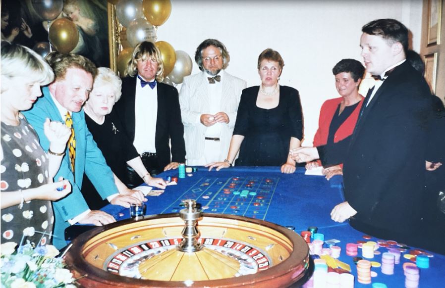 bslade1969's tweet photo. Going through old snaps. This was a Cannizaro anniversary bash. Dad said I'd won the most at the mobile casino but couldn’t take the prize as related. Looking at the @Robin_Askwith pile, I’m not convinced I won! Lovely #DameJuneWhitfield and #PatrickFyffe a little short on chips. https://t.co/gVv0ypuX0A