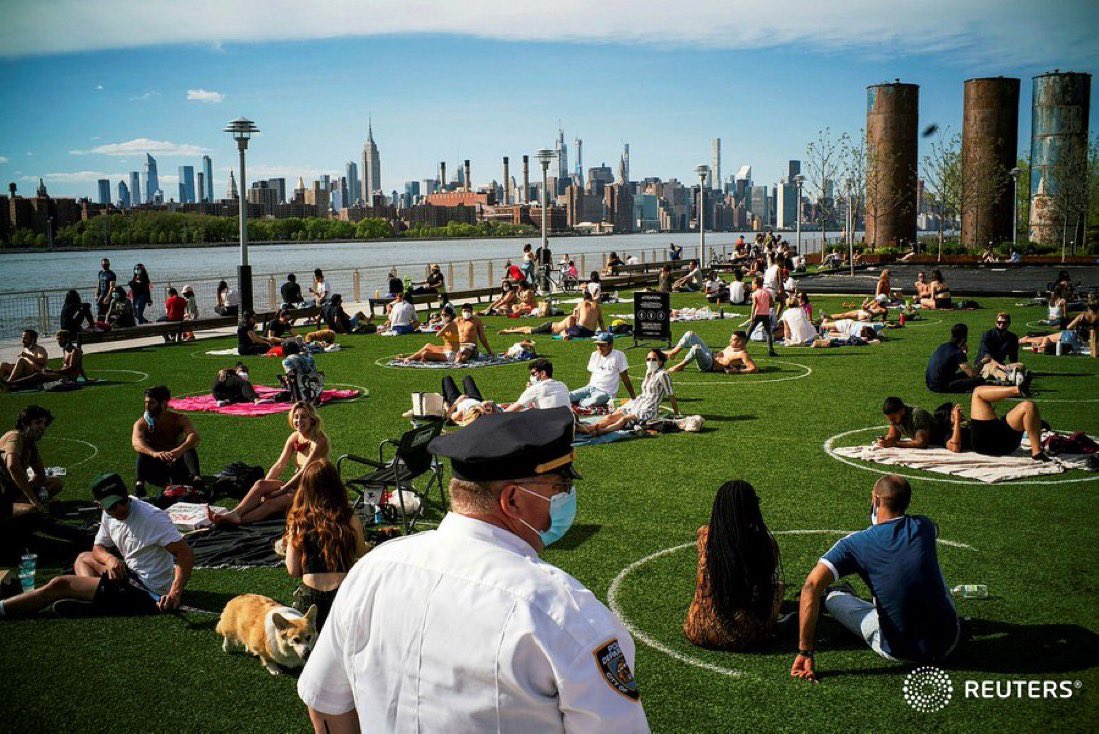 This photo illustrates a strategy the city of New York is using to encourage physical distancing in parks. Notice the circles drawn out on the grass in a well spaced grid.