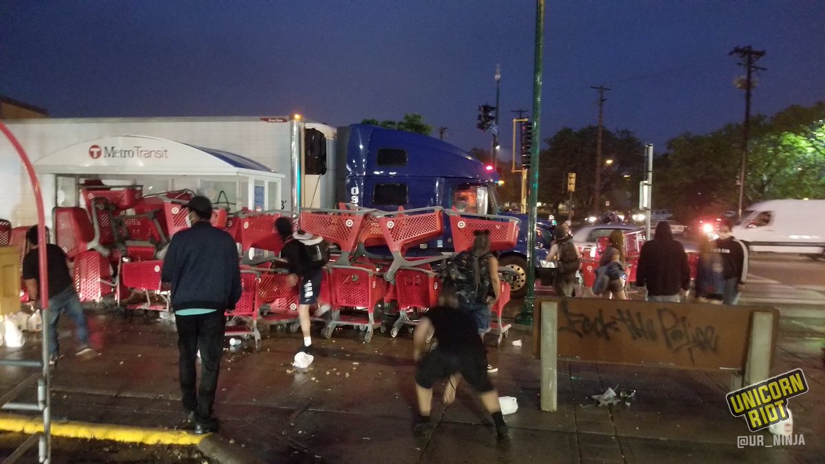 There is currently a dramatic confrontation between protesters and Minneapolis police in the Target parking lot near the MPD 3rd Precinct. Here you can see shopping carts and a semi truck being used as cover from police projectile guns. “The Battle of Snelling and Lake”