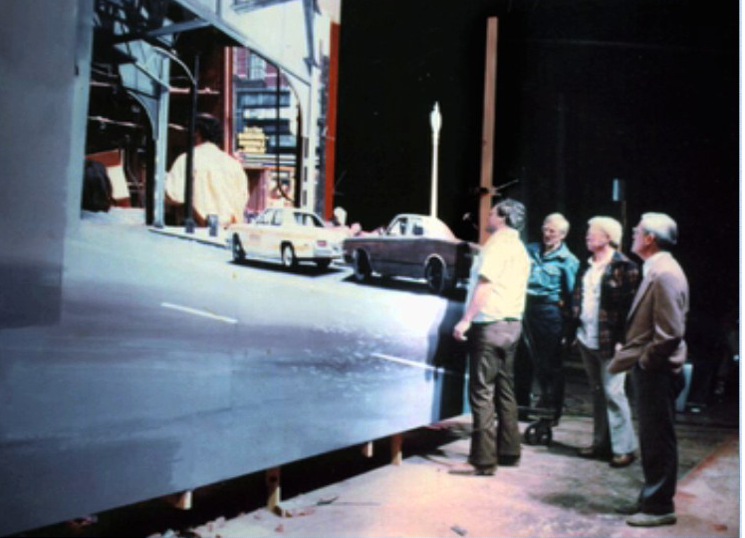 The foreground pieces including the rear car, most of the police car, the roadway, the lamppost and the structure of the elevated train was a painting based on the same photo reference, photographed separately and optically composited against the miniature pyro photography.