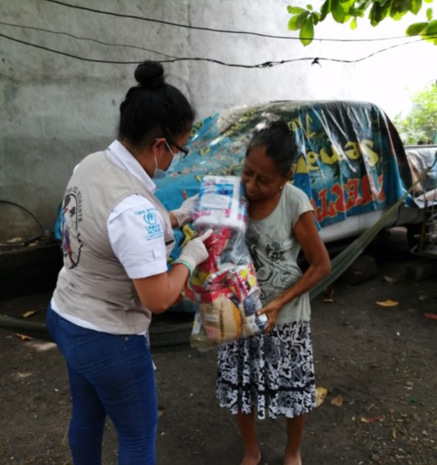 SIMNWorldwide's tweet photo. Trabajadora social de la Casa del Migrante en Tecún Umán, Guatemala, entrega bolsa conteniendo artículos de primera necesidad a familia migrante. #Scalabrinians #SIMN #migrants #refugees https://t.co/Hl70yM6WO9