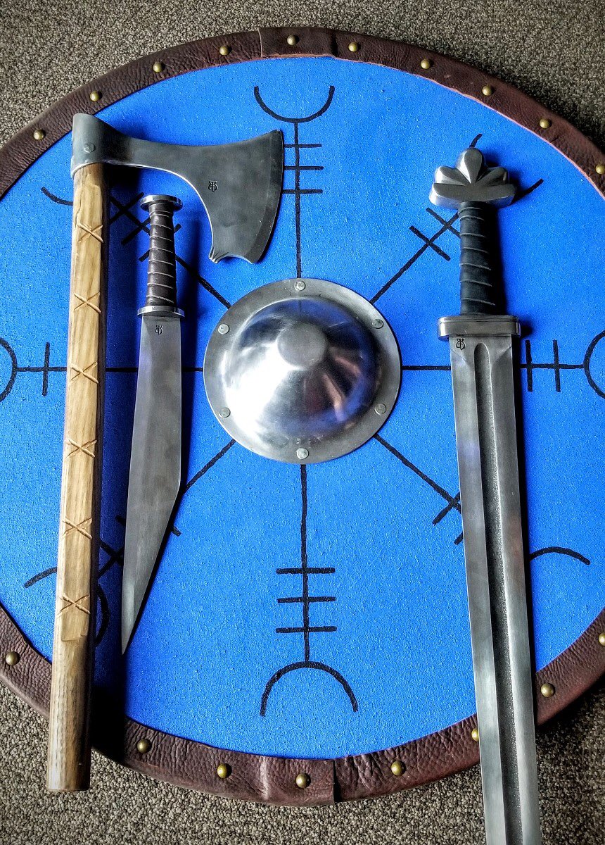 WeSellSwords's tweet photo. Tools of the #Vikings ! 
Bearded #HandAxe, #Scramiseax and Viking #Sword all by the talented folks at Baltimore Knife and Sword All on top of a wooden #Viking #RoundShield made and painted right here in our #yyc #CALGARY Shop and Showroom. #madeinyyc #madeincalgary #shoplocal https://t.co/WuEulI1k41
