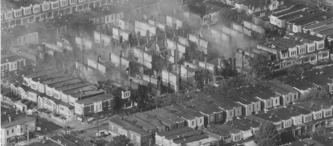 #44: MOVE (Part 2)After an armed conflict in 1985, their house was bombed by a PA police helicopter. Killing 11 & destroying 61 homes, firefighters allowed an hr to pass before putting the fire out. In 90 mins, 10,000 bullets were shot & no one was ever charged for the murders