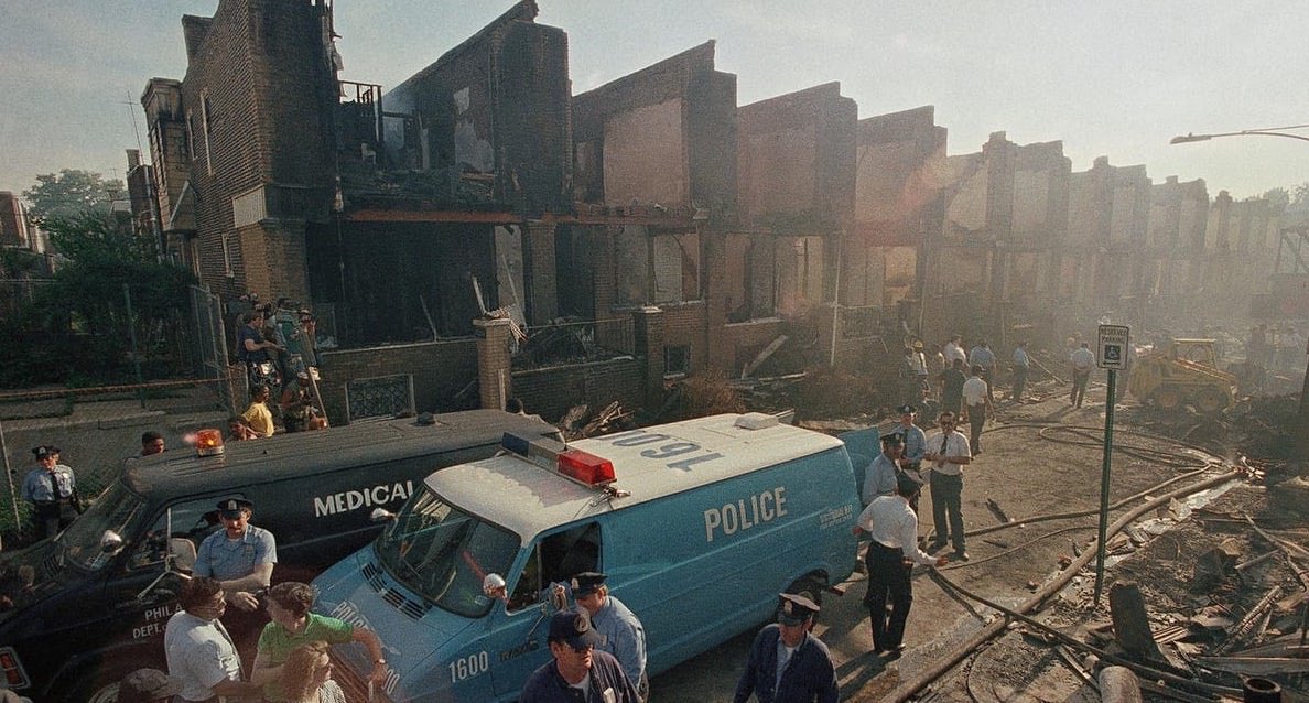 #44: MOVE (Part 2)After an armed conflict in 1985, their house was bombed by a PA police helicopter. Killing 11 & destroying 61 homes, firefighters allowed an hr to pass before putting the fire out. In 90 mins, 10,000 bullets were shot & no one was ever charged for the murders