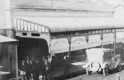 Main St documentary cont: pre & post Covid: 1. Originally Ketteg's, Mick Gonley bought/rebuilt (Winnie Davin's father) here in 1919, CC 0; 2. Cont. as barber/stationers w/diff owners, here Carletons Chemist 1991, CC BY; 3. A Cut Above 2008, CC BY; 4. Now a residence/retail, CC BY