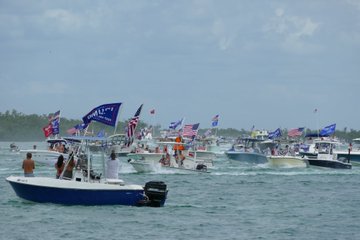 Boats decorated with U.S. and Trump 2020 flags sail by Dolphin Point, Isles of Capri on May 23, 2020.