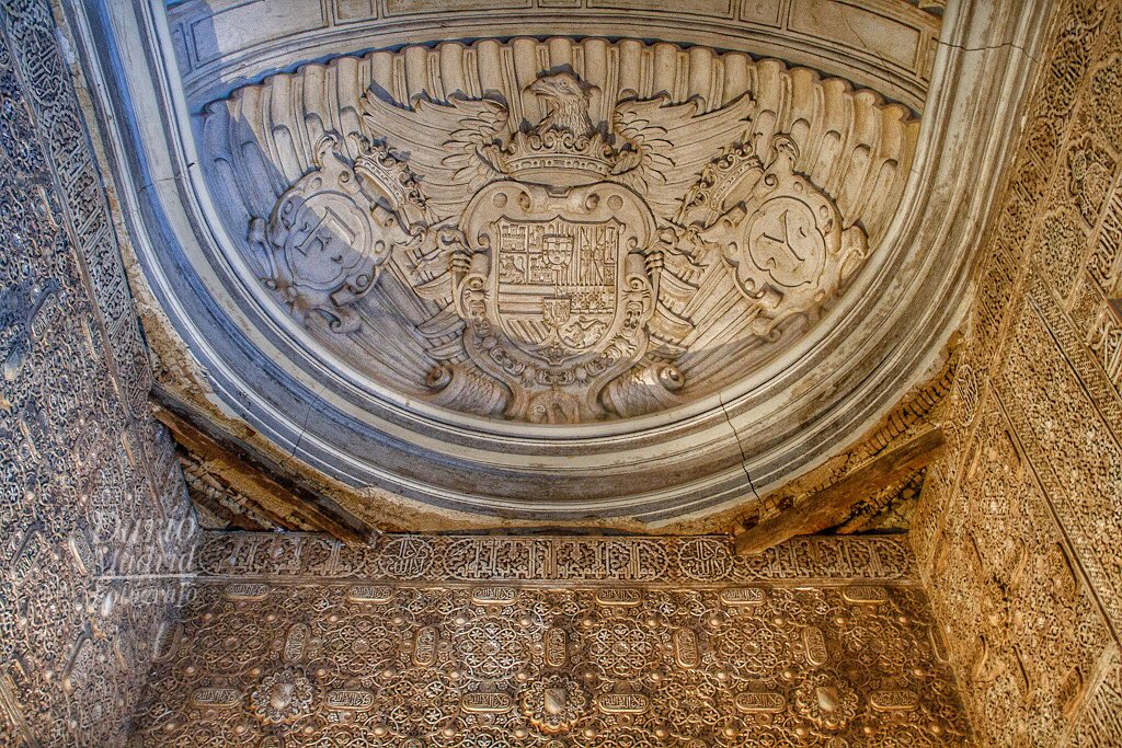 Si alzan la vista en la Sala de los Mocárabes en la Alhambra de Granada verán este escudo con el águila de San Juan. Tranquilos, no lo colocó quién piensan... Tiene a los lados las iniciales de Fernando e Isabel, conquistadores de Granada, y el escudo es de su nieto Felipe II.