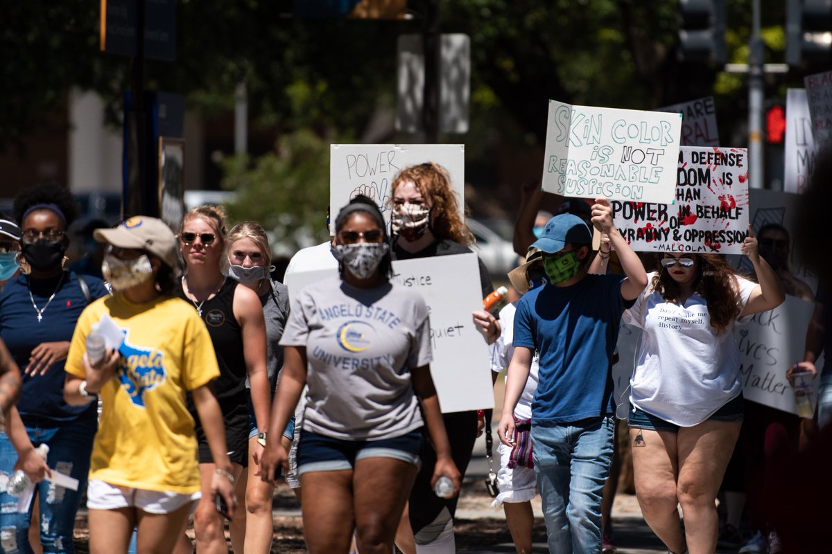 Group of people walking, some holding signs.