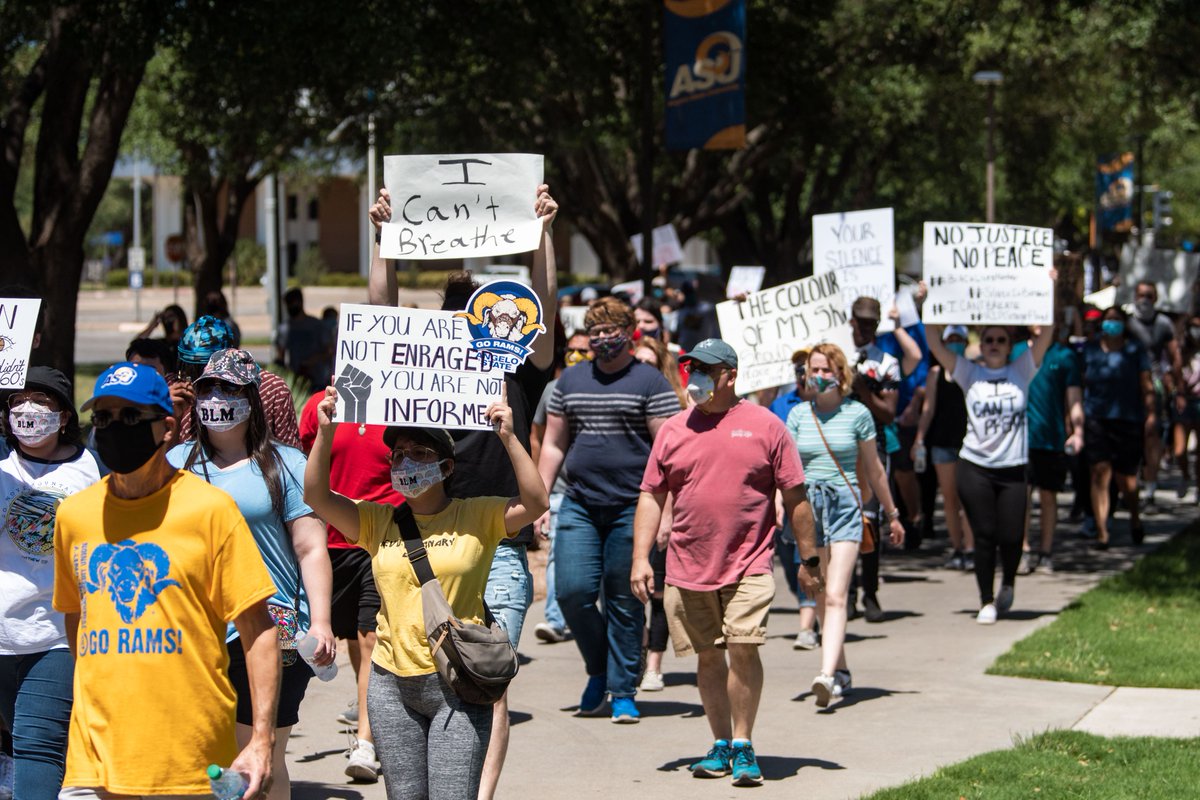 Group of people walking, some holding signs.