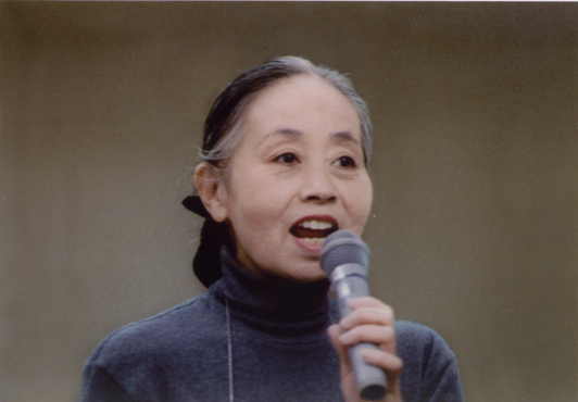 The memorial collection of her writings edited by Seisho Shirani begins with the following speech:[image description: Chinami Kondo, with her hair pulled back and wearing a turtleneck, speaking into a microphone.]