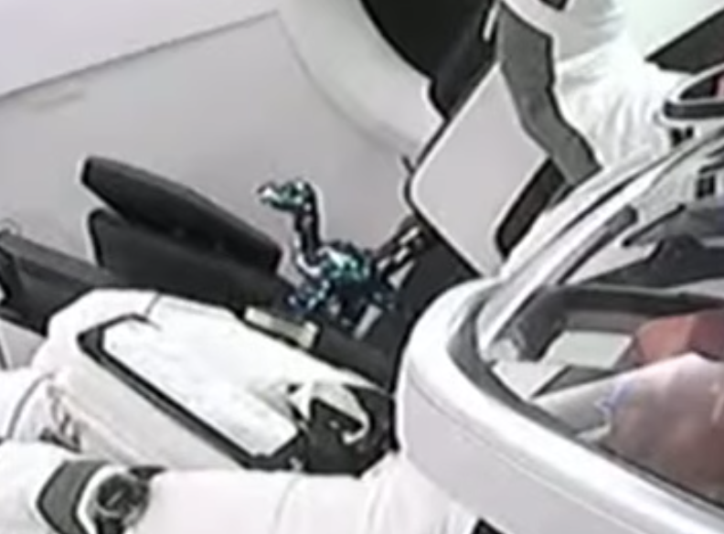 One of the astronauts seems to have brought along a toy dinosaur — astronauts often bring a little plushie or the like on launches, which will start floating when they hit zero g.