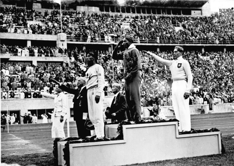 25-Jesse Owens, un athlète olympique afro-américain défie la volonté d’Hitler et les notions de la suprématie aryenne en gagnant la médaille d’or du 100m et performant un salut non hitlérien lors des Jeux Olympiques de 1936. Capturé par Heinrich Hoffman.