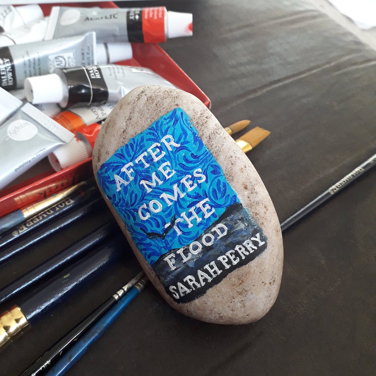 After Me Comes The Flood by  @sarahgperry1 painted on a rock, waiting to be hidden in the library for a reader to find.