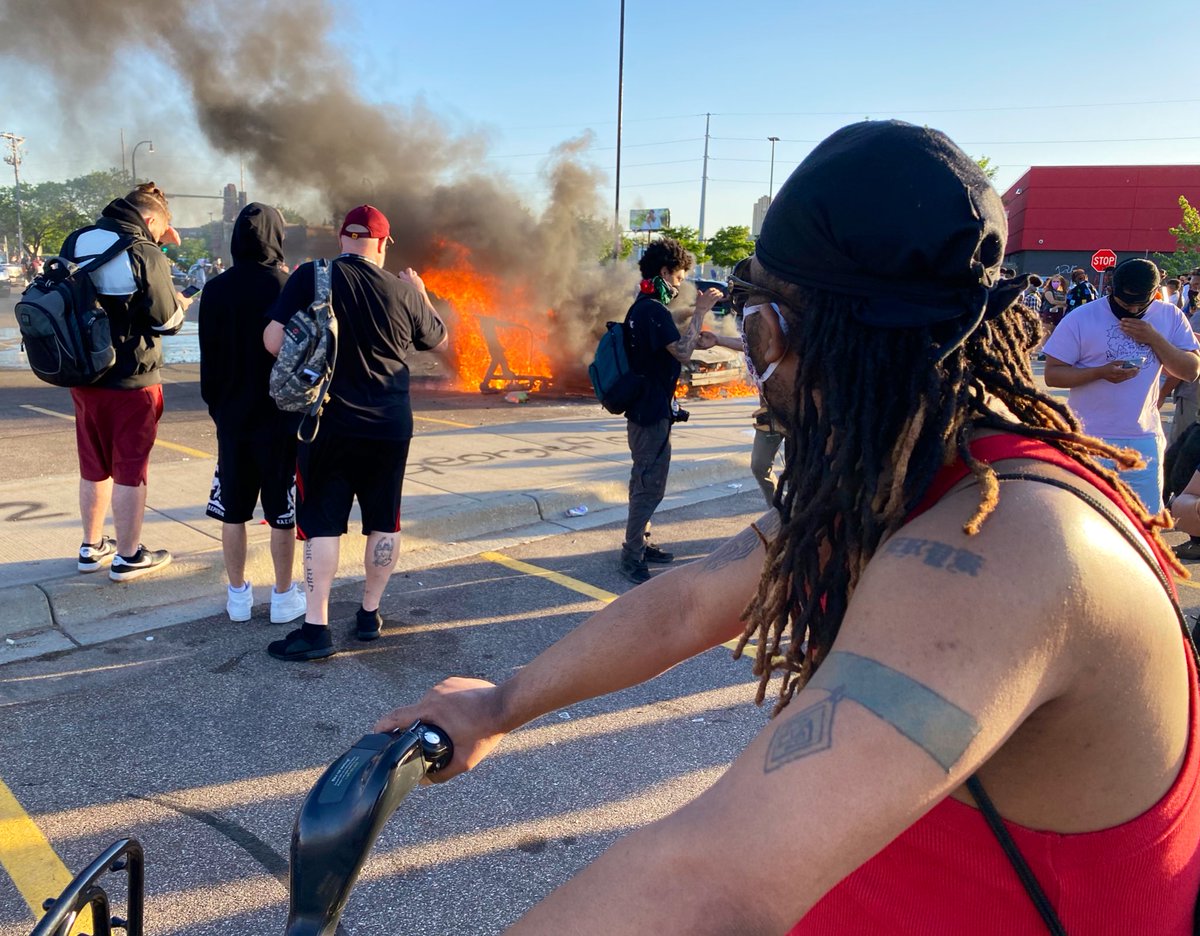 Night three in  #Minneapolis. 500+ people in a looted Target parking lot watching a torched car while a music group plays an acoustic set a few yards away.  #NBCNews – at  Target