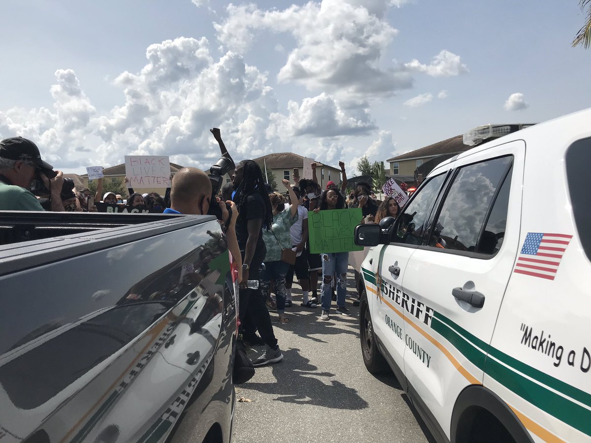 Protestors march down the block, which  @OrangeCoSheriff has blocked off at one end. They went up to a deputy in his car, yelling, “no justice, no peace, no racist police” and “say his name,  #GeorgeFloyd”Other deputies stood by.