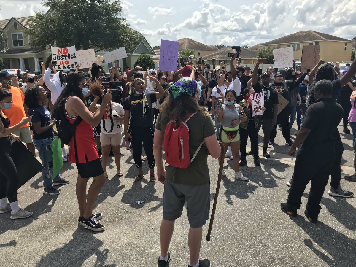 Protestors march down the block, which  @OrangeCoSheriff has blocked off at one end. They went up to a deputy in his car, yelling, “no justice, no peace, no racist police” and “say his name,  #GeorgeFloyd”Other deputies stood by.