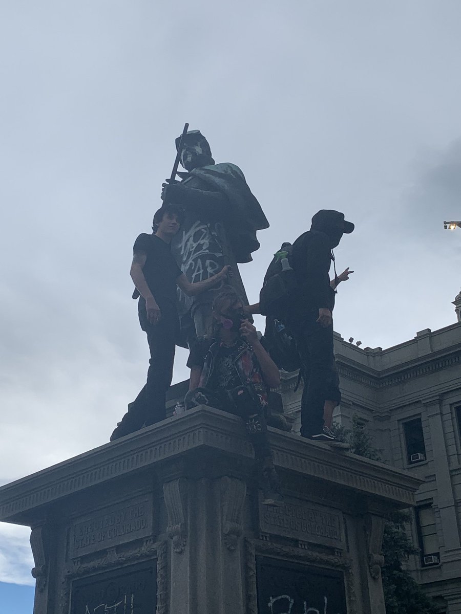 These white young men are spray painting the statue in front of the Colorado Capitol.