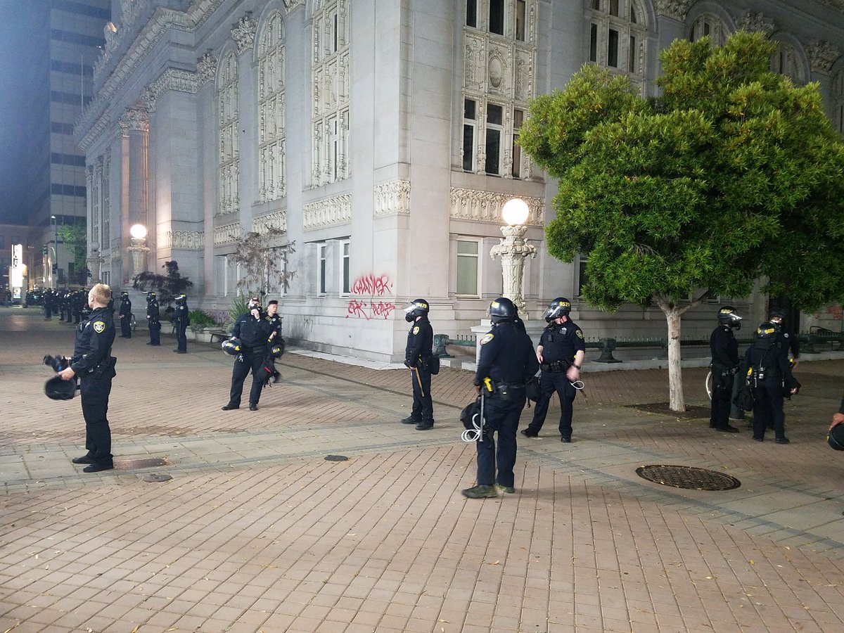 OPD form line around plaza side of city hall. Most have gas masks on.