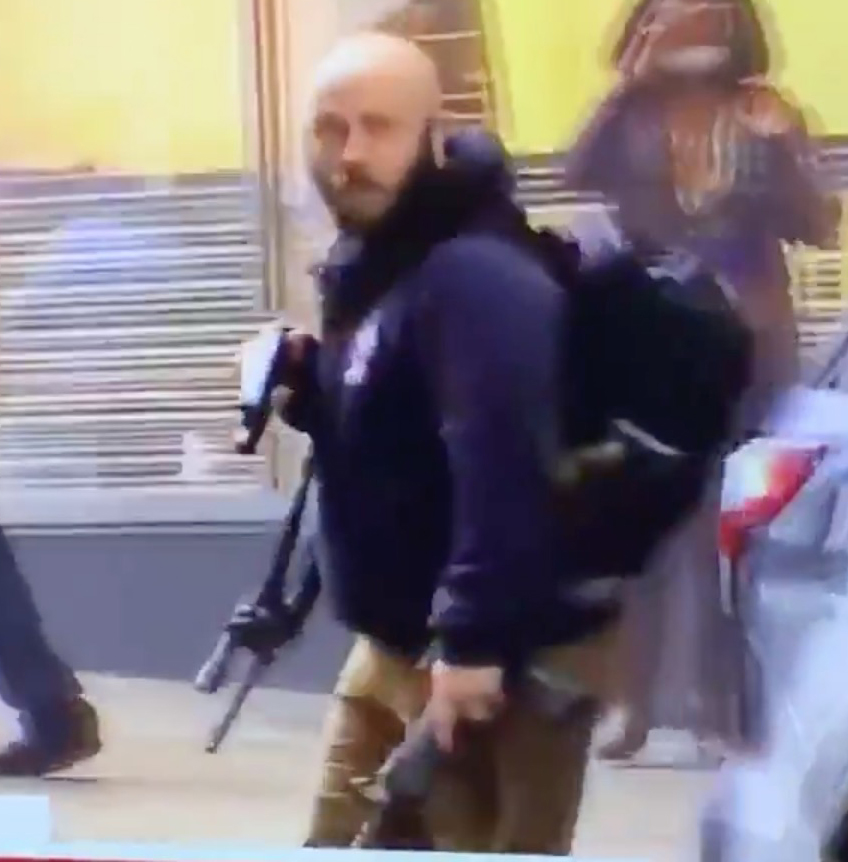 Under his hoodie, this guy is wearing a tactical vest with ammunition pouches.