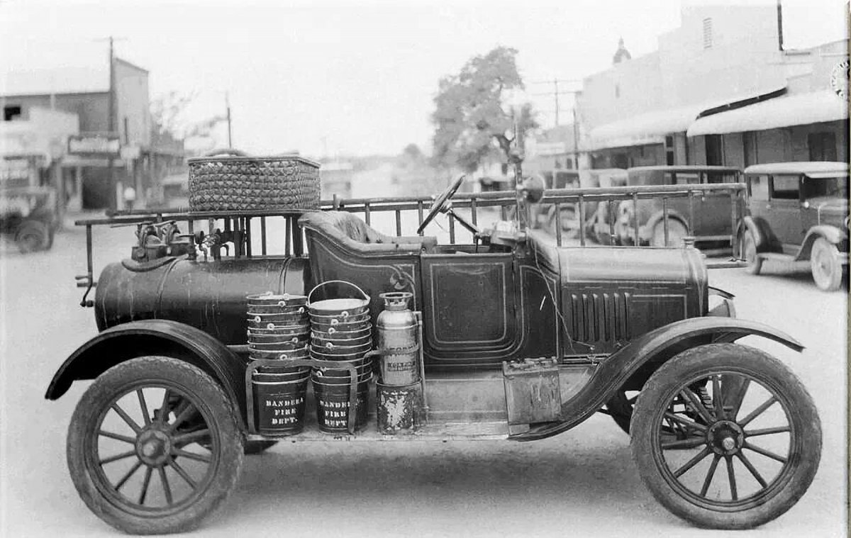 A circa 1915 fire department vehicle in Bandera, Texas. This photo was taken in (roughly) 1930.  On Main Street: you can see the county courthouse in the background. Look at the buckets. Can imagine fighting a fire with a bucket brigade?