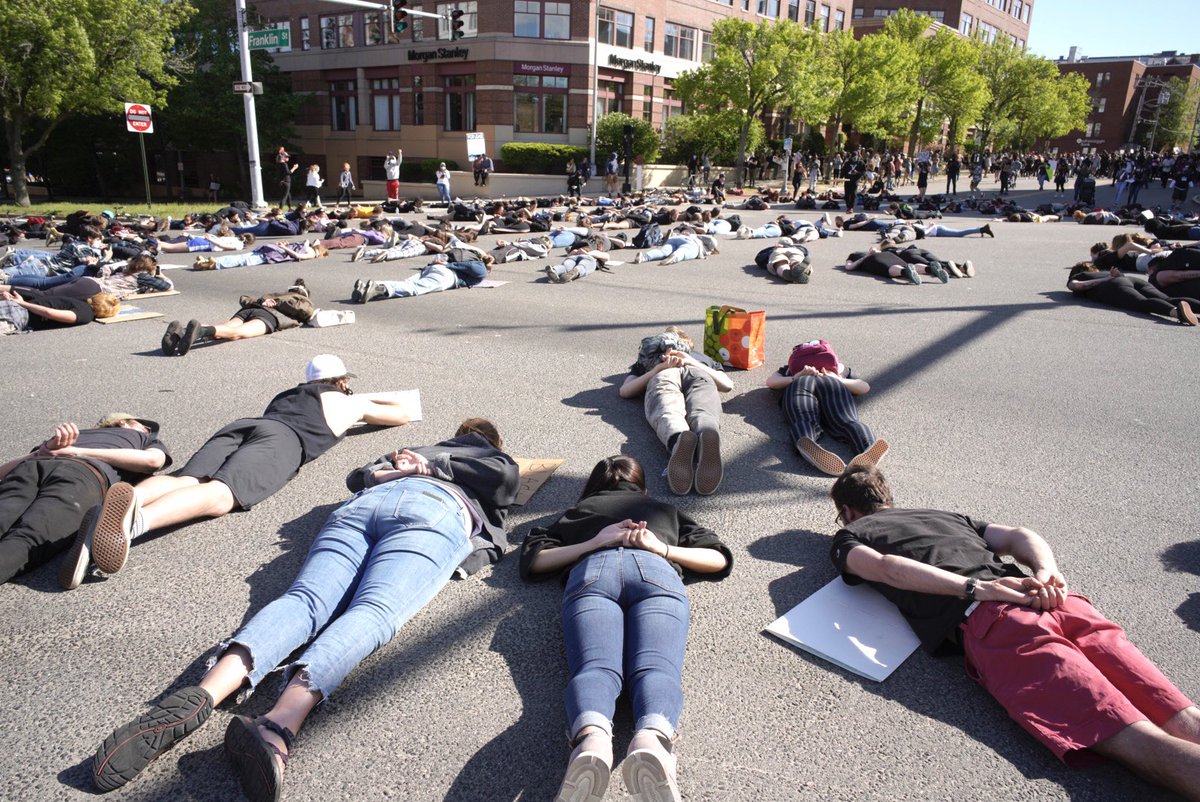 gregoryrec's tweet image. Protestors lie down with their hands behind their backs at the intersection of Franklin Arterial and Middle Street during a protest on Sunday