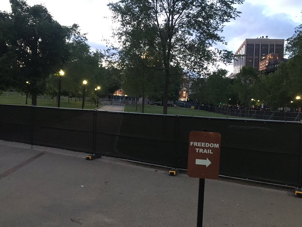 Appears the city has set up a massive fenced in area where folks would usually gather next to the state house; this is filtering most foot traffic through a small gap in the gate up to the street, while also splitting up those who are coming in near Park Street.  #bostonprotest