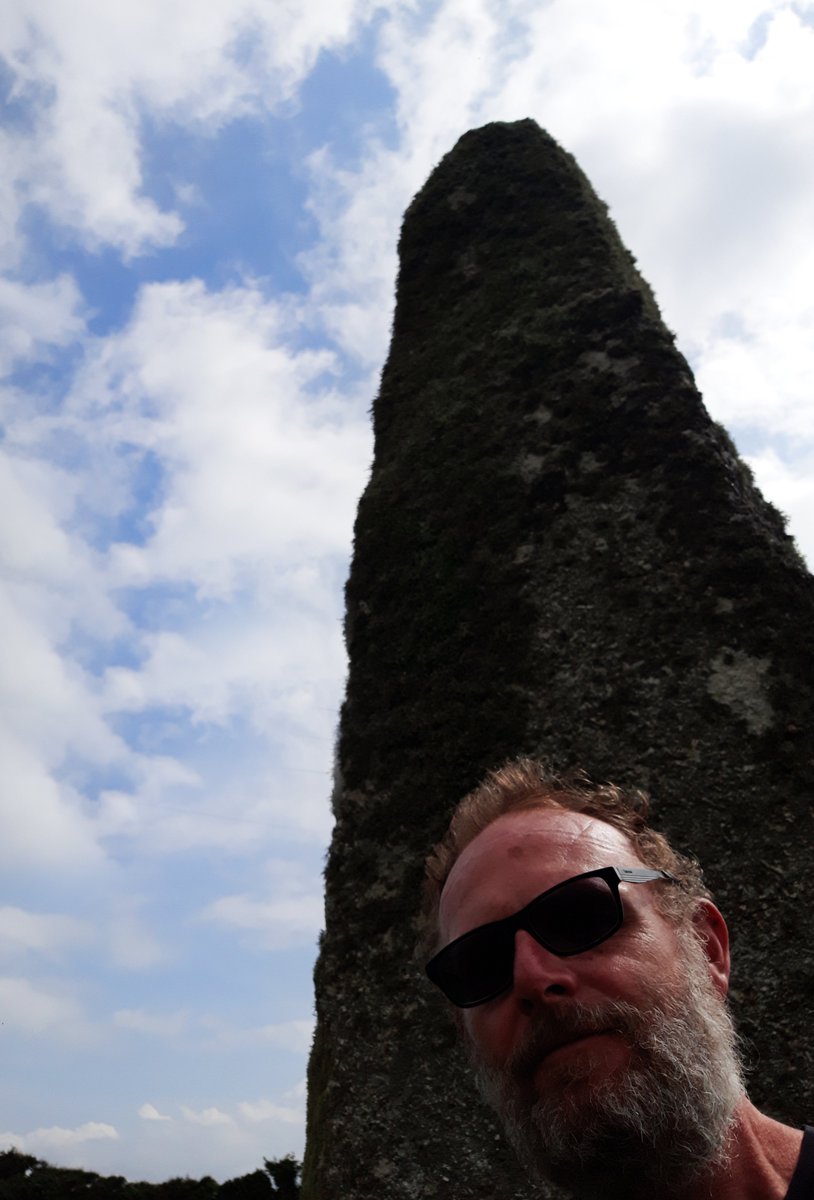 Tresvennack Pillar is a giant of a standing stone. 11.5 ft tall in a field near Kerris. Scruffy photo of me shown for scale; lockdown hair and all, sorry. A scheduled monument - 2 urns containing cremated bones were discovered near its base in 1848. #PrehistoryOfPenwith