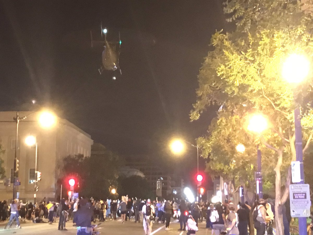 CDGoetteLuciak's tweet photo. Demonstrators are standing firm against the helicopter’s heavy winds. Many are yelling up at it, expressing anger at what they see as a dangerous form of harassing the protesters. Police cars are lined up tightly all down E street behind them. https://t.co/OQjZoA9HDf
